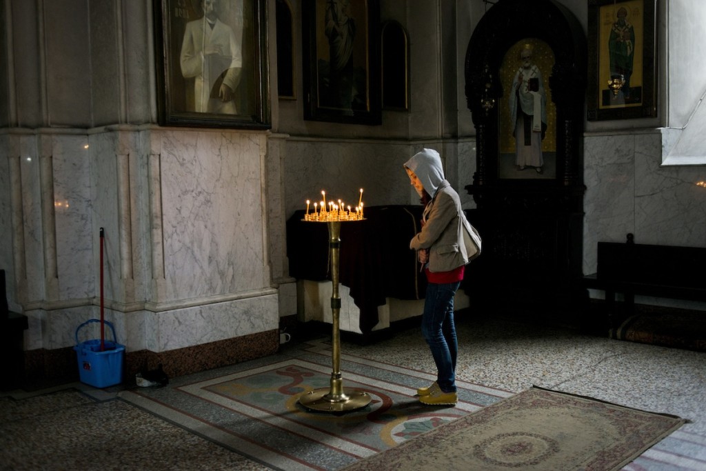 A young Georgian woman lights a candle in Kashveti Church in Tbilisi, Georgia on April 23, 2014. Georgian women are required to cover their heads while in church, and hear choice of a hood instead of a scarf is quite unorthodox.