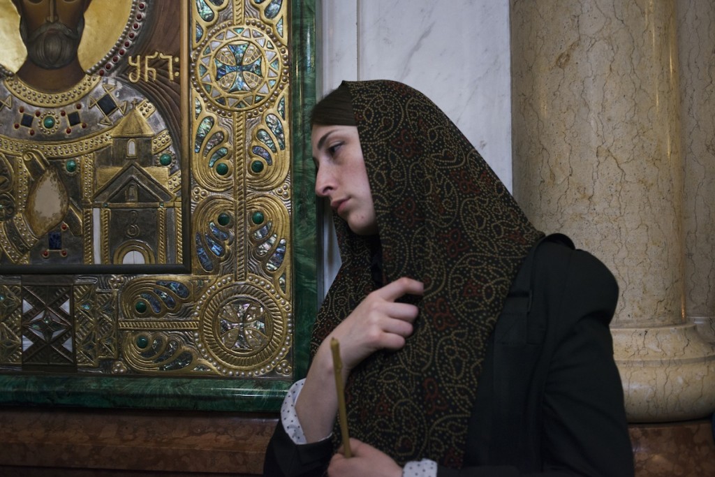 A Georgian woman leans against the icon of a saint in Church of the Trinity in Tbilisi, Georgia on April 27, 2014. The well-respected Patriarch Ilya attends the church each sunday, accompanied by a military guard.