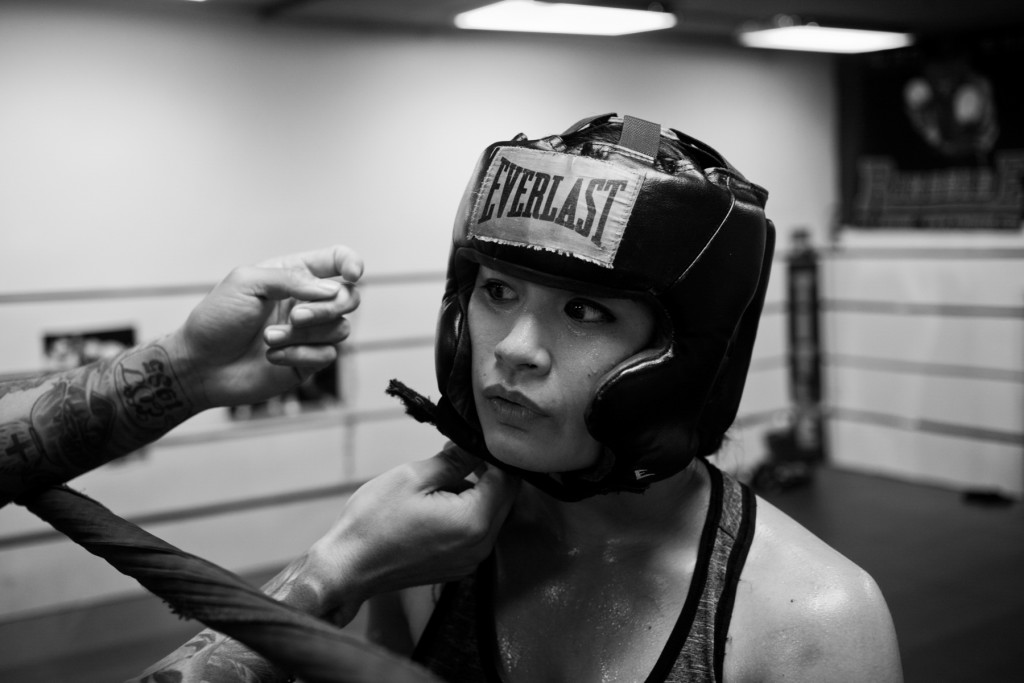 Casey Morton is fitted with a helmet by her full-time coach, Jairo Escobar, before sparring with another female boxer at World Class Boxing Gym in San Francisco, CA.