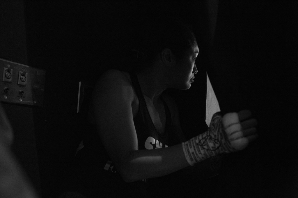 Casey apprehensively peeks through the curtain and scans the crowd as she waits for her name to be called by the announcer for her pro-debut fight.