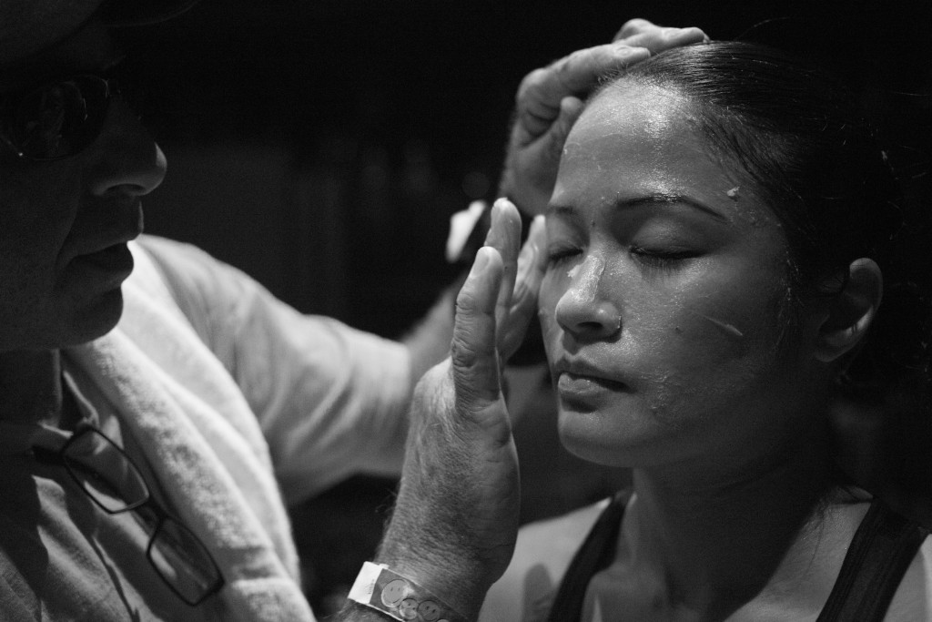 A cutman applies Vaseline to Casey's face to minimize the risk of her skin tearing as a result of being punched by her opponent during the pro-debut fight in Sacramento, CA.